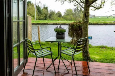 a table and two chairs on a patio near a lake at De koperslager in Watergang