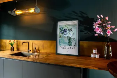 a kitchen counter with a sink and a picture of a vase of flowers at De koperslager in Watergang