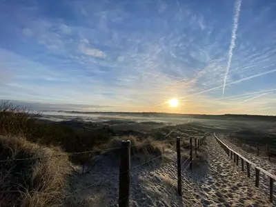 a sunset on a sandy beach with a fence at Het Oude Raadhuis in Noordwijkerhout