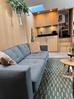 a living room with a blue couch and a kitchen at Het Oude Raadhuis in Noordwijkerhout