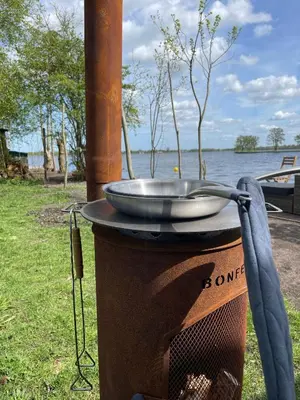 a grill with a bowl on top of it next to the water at Luxury Experience in Off The Grid Lodge at an Amazing Lake Vinkeveense Plassen in Vinkeveen