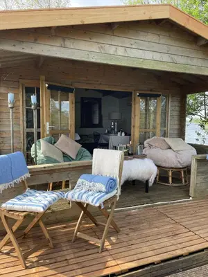 a wooden deck with two chairs and a bedroom at Luxury Experience in Off The Grid Lodge at an Amazing Lake Vinkeveense Plassen in Vinkeveen