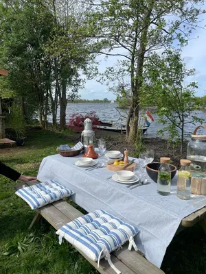 a table with plates of food on it next to the water at Luxury Experience in Off The Grid Lodge at an Amazing Lake Vinkeveense Plassen in Vinkeveen
