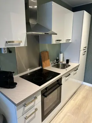 a kitchen with white cabinets and a stove and a sink at De Gouwe Stek in Landsmeer