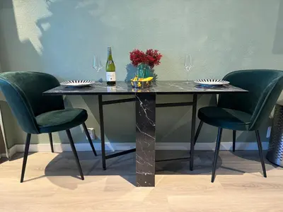 a table with two green chairs and a bottle of wine at De Gouwe Stek in Landsmeer