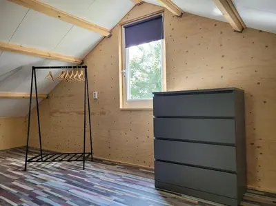 a attic room with a dresser and a window at Gastenverblijf rustig gelegen nabij strand en duin in Heiloo