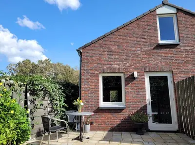 a brick house with a table and a window at Gastenverblijf rustig gelegen nabij strand en duin in Heiloo