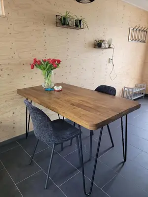 a wooden table with chairs and a vase of flowers at Gastenverblijf rustig gelegen nabij strand en duin in Heiloo