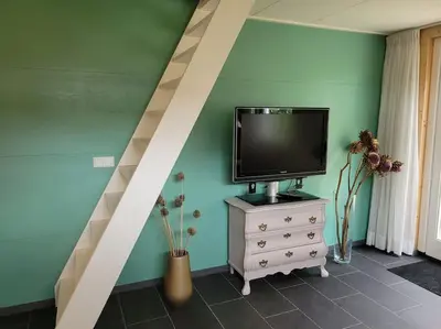 a tv sitting on a dresser in a room at Gastenverblijf rustig gelegen nabij strand en duin in Heiloo
