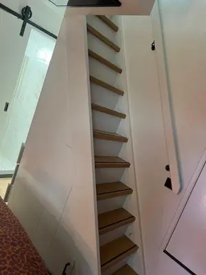 a staircase in a room with a white wall at Cozy & Modern Tiny House in Velserbroek