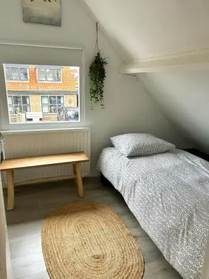 a bedroom with a bed and a window at Beach house met parkeerplaats in het centrum in Egmond aan Zee