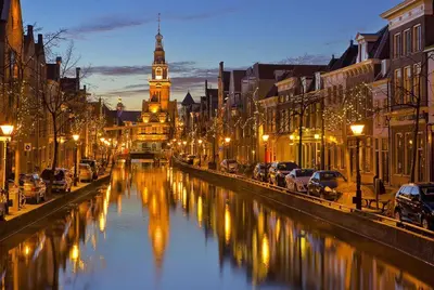 a city street with a river with cars and a clock tower at Beach house met parkeerplaats in het centrum in Egmond aan Zee