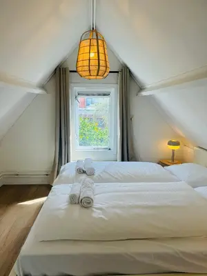 a bedroom with a large white bed with towels on it at Hello Noordwijk - Tiny house Julianastraat 12 in Noordwijk aan Zee