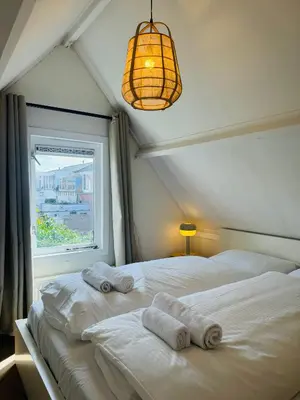 a bedroom with two white beds and a window at Hello Noordwijk - Tiny house Julianastraat 12 in Noordwijk aan Zee