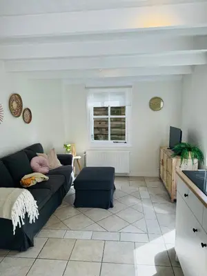 a living room with a black couch and a window at Hello Noordwijk - Tiny house Julianastraat 12 in Noordwijk aan Zee
