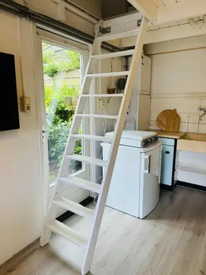 a ladder in a kitchen with a stove and a refrigerator at Hello Noordwijk - Huis ter duinstraat in Noordwijk aan Zee