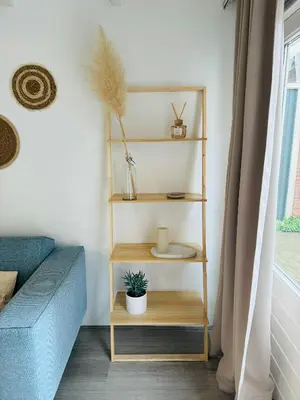 a living room with a blue couch and wooden shelves at Hello Noordwijk - Huis ter duinstraat in Noordwijk aan Zee
