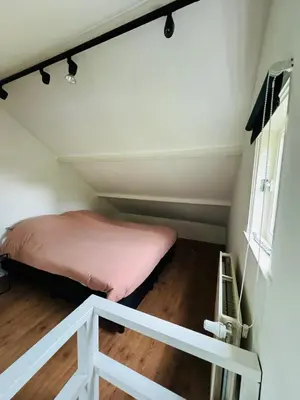 a bed in a small room with a window at Hello Noordwijk - Huis ter duinstraat in Noordwijk aan Zee