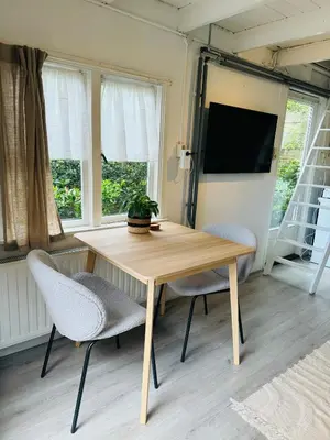 a table and chairs in a room with windows at Hello Noordwijk - Huis ter duinstraat in Noordwijk aan Zee