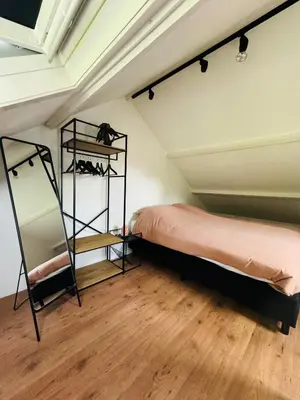 a bedroom with a bed and a shelf in a room at Hello Noordwijk - Huis ter duinstraat in Noordwijk aan Zee