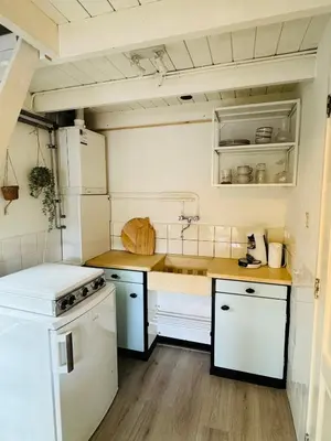 a small kitchen with white cabinets and a sink at Hello Noordwijk - Huis ter duinstraat in Noordwijk aan Zee