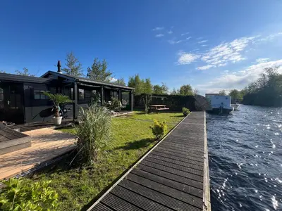 a house on the water with a dock at New- The Cabana- With Sauna and Hot Tub, on a lake near Amsterdam in Vinkeveen
