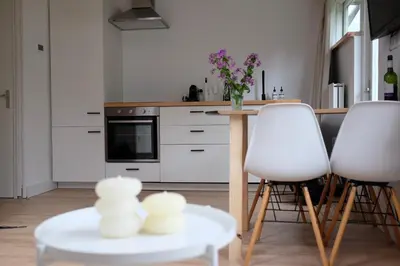 a kitchen with two white chairs and a table at Beach Lodge 24 - Noordwijk aan Zee - met eigen tuin in Noordwijk