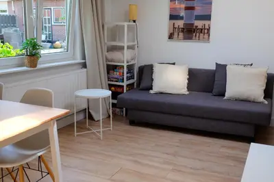 a living room with a couch and a table at Beach Lodge 24 - Noordwijk aan Zee - met eigen tuin in Noordwijk
