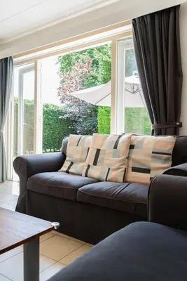 a living room with a couch and a large window at -Duinhuisje - voor families & honden nabij strand in Noordwijk