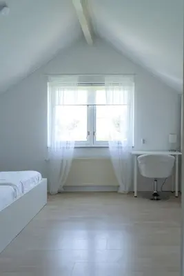 a white bedroom with a bed and a window at -Duinhuisje - voor families & honden nabij strand in Noordwijk