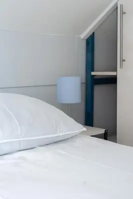 a white bed with a white pillow on it at -Duinhuisje - voor families & honden nabij strand in Noordwijk