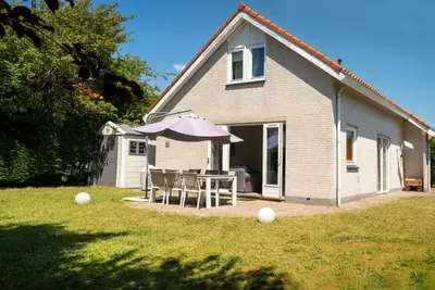a house with a table and an umbrella in the yard at -Duinhuisje - voor families & honden nabij strand in Noordwijk