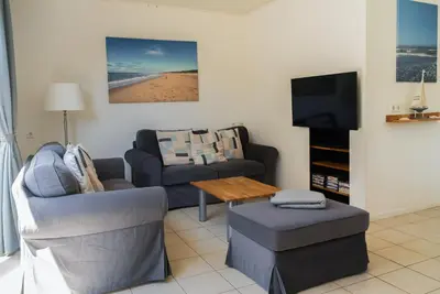 a living room with a couch and a tv at -Duinhuisje - voor families & honden nabij strand in Noordwijk