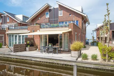 a house with a patio next to a river at Meerzicht 59 - Ideal family appt for 6 persons in Uitgeest
