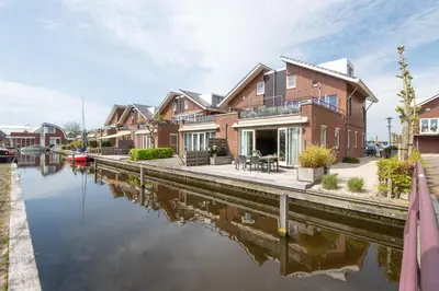 a house next to a canal with a house at Meerzicht 59 - Ideal family appt for 6 persons in Uitgeest
