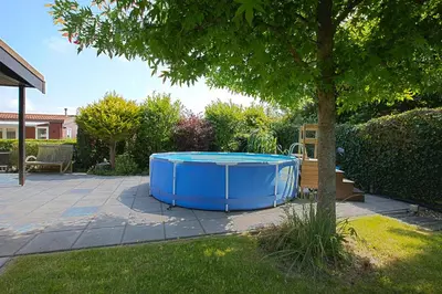 a blue tub sitting next to a tree in a yard at Jamies Cottage Warmenhuizen nu met airco in Warmenhuizen