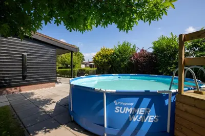 a hot tub in a yard next to a house at Jamies Cottage Warmenhuizen nu met airco in Warmenhuizen