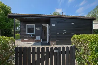 a black shed with a fence in front of it at Jamies Cottage Warmenhuizen nu met airco in Warmenhuizen
