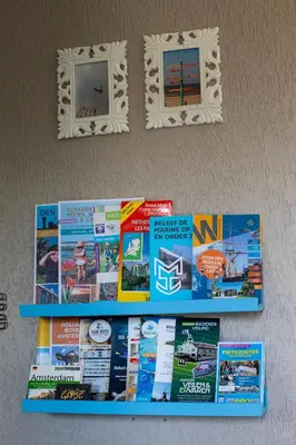 a display of magazines on a wall with two mirrors at Jamies Cottage Warmenhuizen nu met airco in Warmenhuizen
