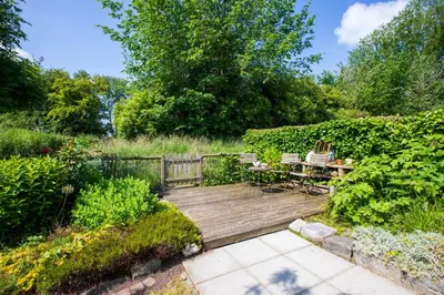a wooden deck with a table and chairs in a garden at Jamies Cottage Warmenhuizen nu met airco in Warmenhuizen
