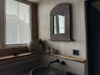 a bathroom with a sink and a mirror and a window at Bed and Breakfast Lokaal Wadway in Spanbroek
