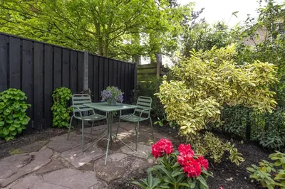 a table and chairs in a garden with flowers at Cosy Dutch Delight Apartment in Santpoort-Zuid