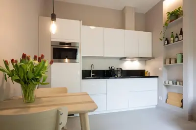 a kitchen with white cabinets and a table with a vase of flowers at Cosy Dutch Delight Apartment in Santpoort-Zuid