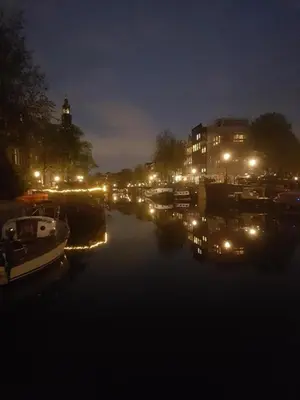 a city at night with boats in the water at Pantheos Top Houseboat in Amsterdam