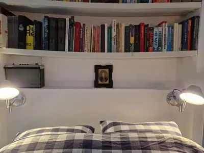a bedroom with a bed with books on a shelf at Pantheos Top Houseboat in Amsterdam