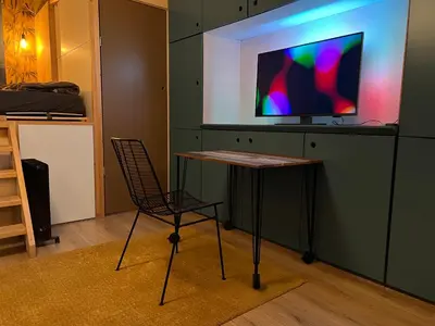 a table and a chair in a room with a tv at A tiny house - Amsterdam region in Lelystad