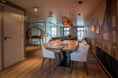 a dining room with a wooden table and white chairs at Hotel Cornelisz in Amsterdam