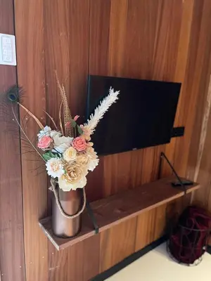 a vase of flowers on a shelf next to a tv at Ben's Cabine - De Hollandse Boerderij in Bodegraven