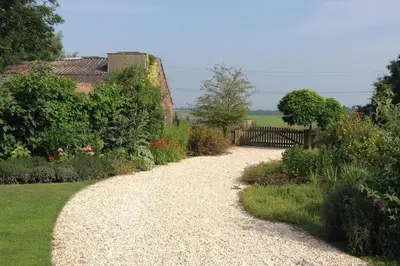 a gravel path in a garden with a fence at Riante Boerderij in Het Groene Hart Regio Utrecht in Oudewater