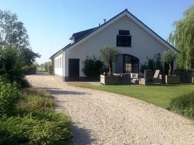 a white house with a gravel road in front of it at Riante Boerderij in Het Groene Hart Regio Utrecht in Oudewater